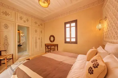 a bedroom with a bed and a window and a table at Riad Dar Arwa in Marrakech