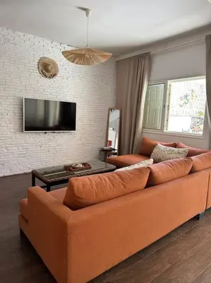 an orange couch in a living room with a tv at Maison de ville avec piscine privée in Marrakech