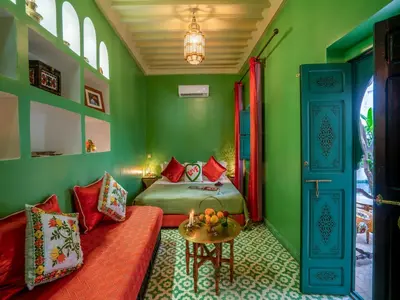 a green bedroom with a bed and a table at Riad dada Messouda spa in Marrakech