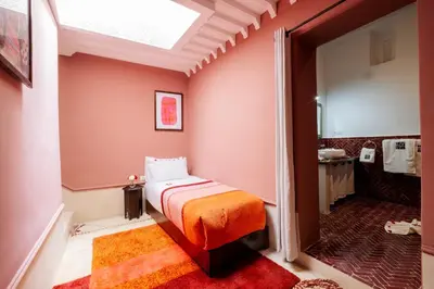 a bedroom with a bed and a bathroom with a tub at Riad Zi in Marrakech