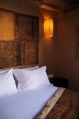 a bedroom with a bed with white pillows and a lamp at Riad Zi in Marrakech