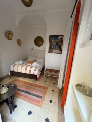 a small bedroom with a bed and a table at Le riad de l'étoile ocre - COTG in Marrakech