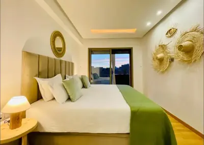 a bedroom with a large white bed and a window at Appartement luxueux avec vue panoramique sur l’Atlas au centre de Marrakech in Marrakech