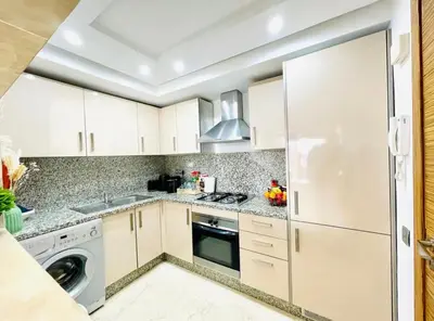 a kitchen with white cabinets and a washer and dryer at Appartement luxueux avec vue panoramique sur l’Atlas au centre de Marrakech in Marrakech