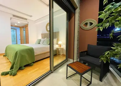 a bedroom with a bed and a chair and a mirror at Appartement luxueux avec vue panoramique sur l’Atlas au centre de Marrakech in Marrakech