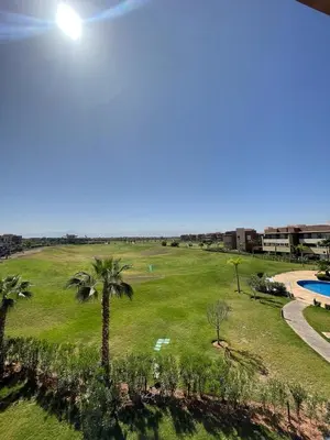 a view of a park with a pool and palm trees at Marrakech Prestigia 3 chambres in Marrakech