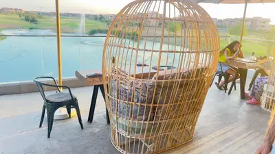 a large bird cage sitting next to a table at mini-villa situee dans une residence Prestigia à Marrakech, avec une vue sur la piscine et le golf une securite 24h sur 24 et une proximite ideale de l aeroport 5 minutes C est une offre parfaite pour des vacances in Marrakech