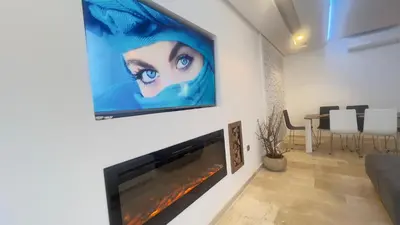a living room with a large tv hanging on a wall at mini-villa situee dans une residence Prestigia à Marrakech, avec une vue sur la piscine et le golf une securite 24h sur 24 et une proximite ideale de l aeroport 5 minutes C est une offre parfaite pour des vacances in Marrakech