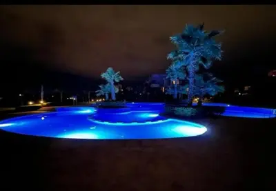 a pool with blue lights in a yard at night at Appartement de Luxe avec Jardin Vue sur la Piscine Golf Securise 24h sur 24 a 5 Minutes de l Aeroport in Marrakech
