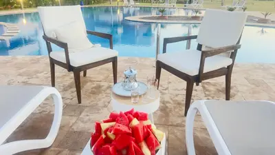 two chairs and a table with a bowl of fruit at Appartement de Luxe avec Jardin Vue sur la Piscine Golf Securise 24h sur 24 a 5 Minutes de l Aeroport in Marrakech