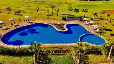 an overhead view of a swimming pool with palm trees and umbrellas at Appartement de Luxe avec Jardin Vue sur la Piscine Golf Securise 24h sur 24 a 5 Minutes de l Aeroport in Marrakech