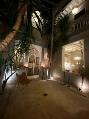 a room with palm trees and a room with a chair at Riad Kismet Marrakech in Marrakech