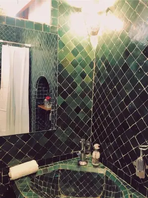 a green tiled bathroom with a sink and a mirror at NOSADE Venue in Marrakech