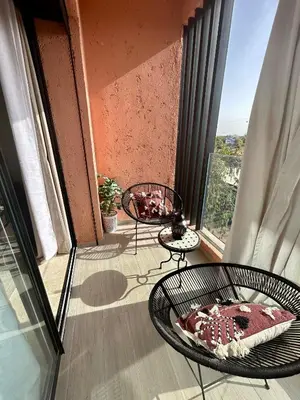 a balcony with two chairs and a table on a balcony at Cosy appartement au Domaine de Noria in Marrakech