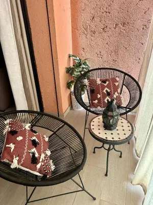 a patio with two chairs and a table with a pillow at Cosy appartement au Domaine de Noria in Marrakech