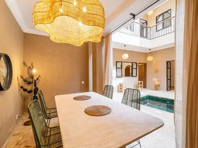 a dining room with a table and a swimming pool at Serenity Riad with Breakfast in Marrakech
