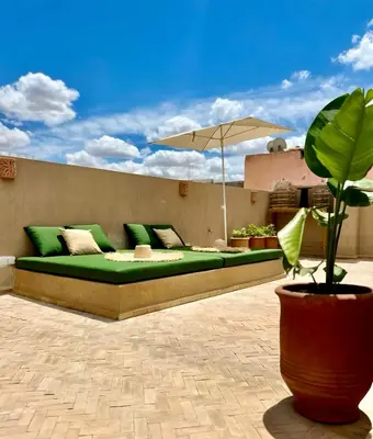 a green couch on a patio with an umbrella at Serenity Riad with Breakfast in Marrakech
