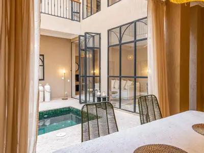 a room with a pool and a table and chairs at Serenity Riad with Breakfast in Marrakech