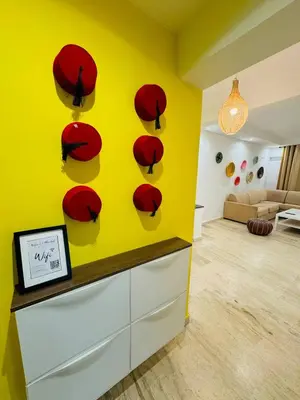 a yellow room with red hats on a wall at Le Gueliz Centeral cosy Suite in Marrakech