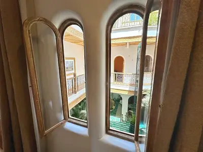 an empty room with two windows and a balcony at Riad Nesayam - Riad Privatisé - 3 Suites - Piscine Chauffée in Marrakech