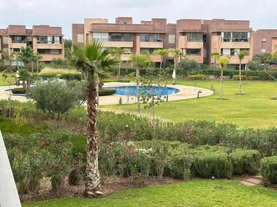 a palm tree in a park in front of a building at Appartement avec Piscine Prestigia Agate Marrakech in Marrakech