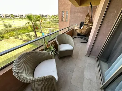 a balcony with wicker chairs and a computer on it at Appartement avec Piscine Prestigia Agate Marrakech in Marrakech