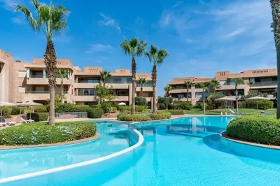 a swimming pool with palm trees in front of a building at Relax front of Golf-Pool-Topaze in Marrakech