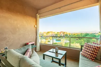 a living room with a couch and a large window at PO 10 Appartement de luxe, golf, piscine & club house in Marrakech