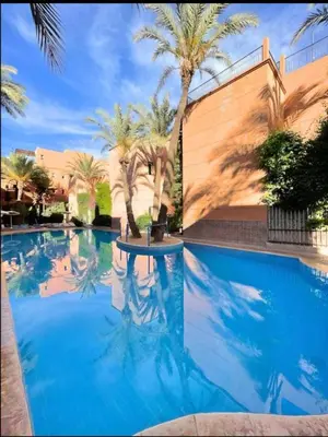 a swimming pool with blue water and palm trees at Riad marrakech boujloud in Marrakech