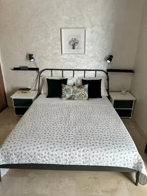 a bedroom with a large bed with two tables and two lamps at Appartement Zazat in Marrakech