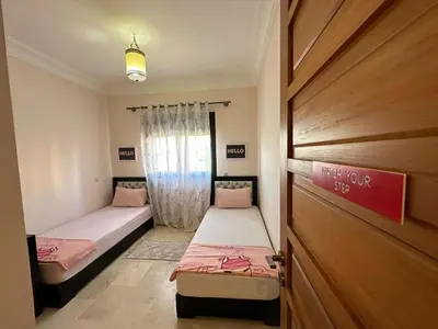 a room with two beds and a door with a window at Résidence Dar Damana Palmeraie Marrakech in Marrakech