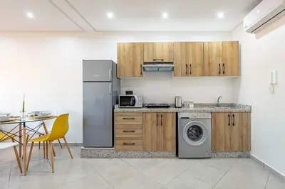 a kitchen with a stainless steel refrigerator and a table at R35 Paisible et tout confort : Netflix+parking+Wifi gratuit in Marrakech