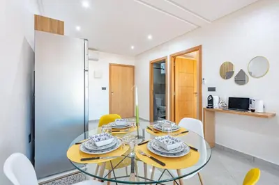 a dining room with a glass table and chairs at R35 Paisible et tout confort : Netflix+parking+Wifi gratuit in Marrakech