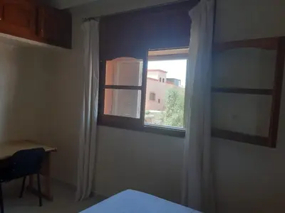 a bedroom with a window and a table and a chair at Calm Cosy Villa in Marrakech