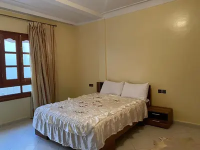 a bedroom with a bed with white sheets and a window at Calm Cosy Villa in Marrakech