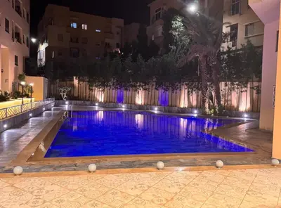 a large swimming pool with blue water at night at appartement 3 chambres avec piscine in Marrakech