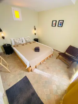 a bedroom with a large bed and a chair at Riad Fiora, private home!!! in Marrakech