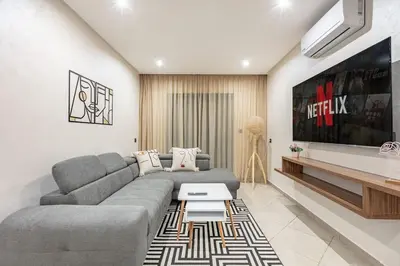 a living room with a gray couch and a tv at RA26 Elegant&Chaleureux Netflix et parking gratuit in Marrakech