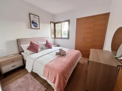 a bedroom with a bed with pink sheets and a dresser at Golf stay with Atlas view at Marrakech! in Marrakech