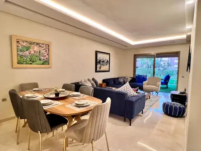 a living room with a table and a blue couch at Golf stay with Atlas view at Marrakech! in Marrakech