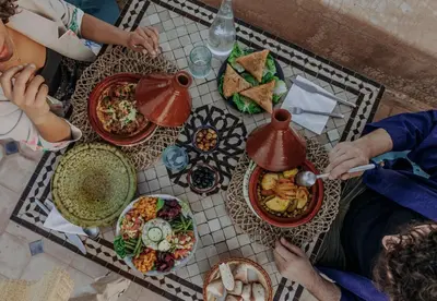 a group of people sitting at a table with food at Riad VUE D'AGDAL in Marrakech