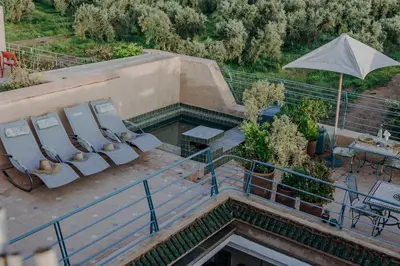 an outdoor swimming pool with chairs and an umbrella at Riad VUE D'AGDAL in Marrakech