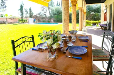 a wooden table with plates and a vase of flowers on it at Villa Dar Sultan - Marrakech in Marrakech