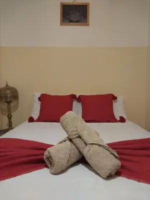 a stuffed animal on a bed with red pillows at Riad Flottement Des Songes in Marrakech