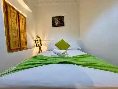 a bedroom with a white bed with a green blanket at Riad Flottement Des Songes in Marrakech
