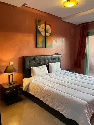 a bedroom with a large bed and a table with a lamp at Cosy Appartement Avec Piscine in Marrakech