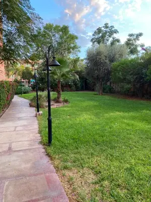 a street light on the grass next to a sidewalk at Cosy Appartement Avec Piscine in Marrakech