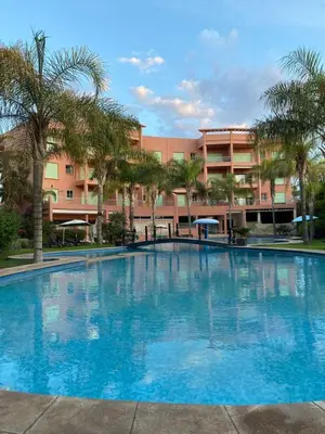 a large blue swimming pool in front of a building at Cosy Appartement Avec Piscine in Marrakech
