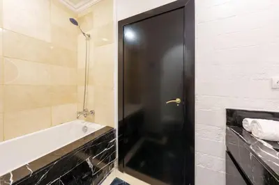 a bathroom with a bath tub and a black door at Luxury Place M Avenue in Marrakech