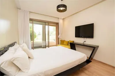 a bedroom with a large bed with a tv on the wall at Relax Front Of Pool-Golf-Atlas in Marrakech
